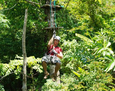 İnsanoğlu, etrafını saran kalın ormandan geçen bir ip üzerinde keyifli bir yolculuğun tadını çıkarıyor..