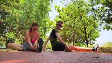 Renkli bir yoga minderinde bacaklarını açarken bir erkek bir kadına yardım ediyor..