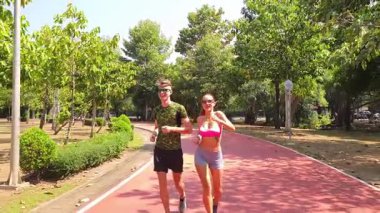 Bir adam ve bir kadın güzel bir parkta birlikte koşuyorlar, temiz havanın tadını çıkarıyorlar.