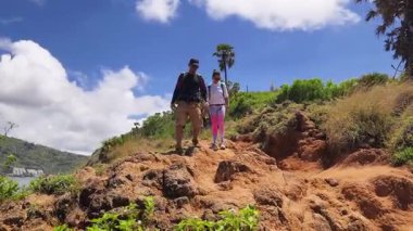 Genç bir çift okyanus manzarası sunan engebeli kayalık bir uçurumda yürüyüş yapıyor..