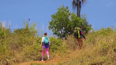 Genç bir çift okyanus manzarası sunan engebeli kayalık bir uçurumda yürüyüş yapıyor..