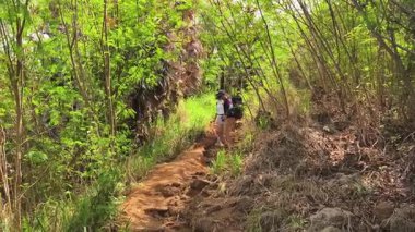 Genç bir çift okyanus manzarası sunan engebeli kayalık bir uçurumda yürüyüş yapıyor..