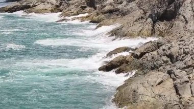 Turkuaz su, kayalık kayalıklar ve yemyeşil tepelerle güzel bir sahil şeridi.