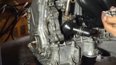 Servis elemanı özenle garajın içindeki bir araba motoru üzerinde çalışıyor..