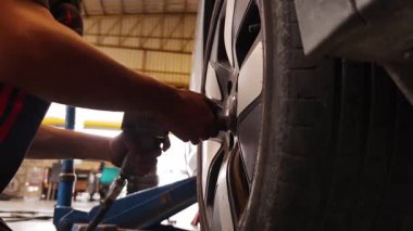 Yetenekli bir tamirci, güvenlik ve bakım sağlamak için lastik değiştirmek için elektrikli bir araç kullanır..