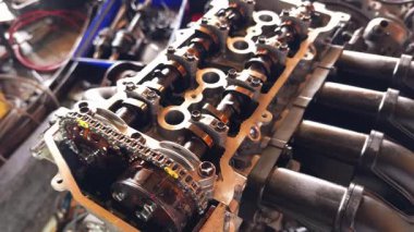 Servis elemanı özenle garajın içindeki bir araba motoru üzerinde çalışıyor..