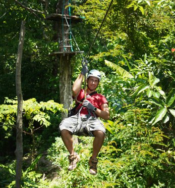İnsanoğlu, etrafını saran kalın ormandan geçen bir ip üzerinde keyifli bir yolculuğun tadını çıkarıyor..