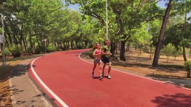 Bir adam ve bir kadın güzel bir parkta birlikte koşuyorlar, temiz havanın tadını çıkarıyorlar.