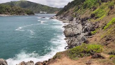 Turkuaz su, kayalık kayalıklar ve yemyeşil tepelerle güzel bir sahil şeridi.