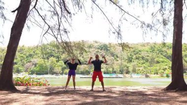 Bir adam ve bir kadın parkta birlikte esneme egzersizleri yapıyorlar..