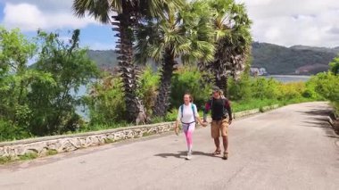 Bir erkek ve bir kadın, doğa güzelliği ve sükunetle çevrili bir yolda rahatça yürüyorlar..