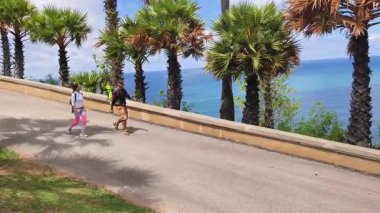 Bir erkek ve bir kadın, doğa güzelliği ve sükunetle çevrili bir yolda rahatça yürüyorlar..