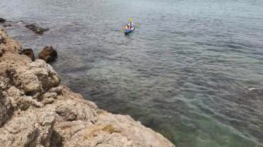 Genç çift, açık mavi bir kanoyla birlikte sarı raketlerle mutlu bir şekilde yol alıyorlar..