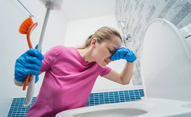 Genç ev hanımı banyodaki klozeti özenle temizler ve yıkar..