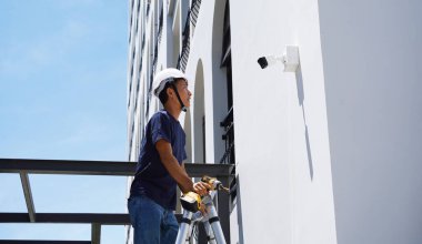 Bir teknisyen konut binasının ön cephesine kamera yerleştiriyor..