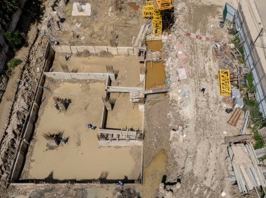 Çeşitli makine ve malzemelerin etrafa saçıldığı yoğun inşaat alanı.