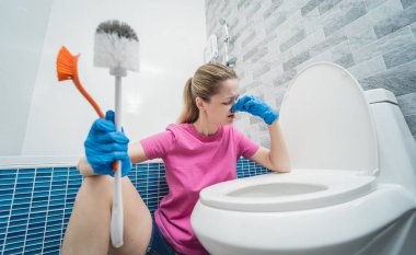 Genç ev hanımı banyodaki klozeti özenle temizler ve yıkar..