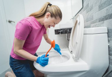 Genç ev hanımı banyodaki klozeti özenle temizler ve yıkar..