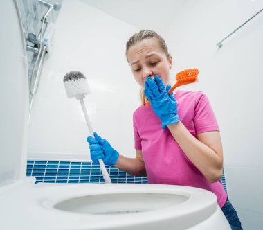 Genç ev hanımı banyodaki klozeti özenle temizler ve yıkar..