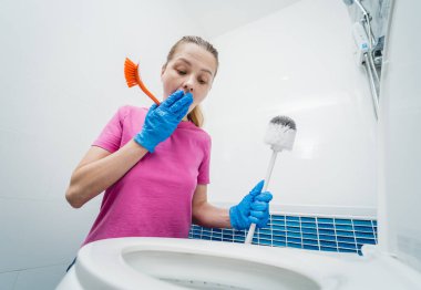 Genç ev hanımı banyodaki klozeti özenle temizler ve yıkar..