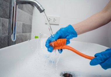 Genç ev hanımı banyodaki lavaboyu özenle temizler ve yıkar..