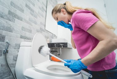 Genç ev hanımı banyodaki klozeti özenle temizler ve yıkar..