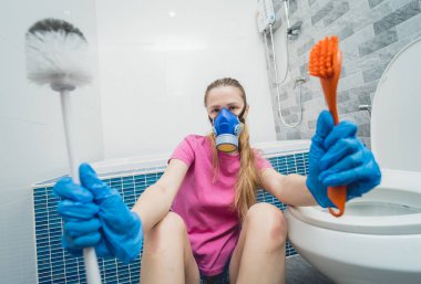 Genç ev hanımı banyodaki klozeti özenle temizler ve yıkar..