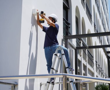 Bir teknisyen konut binasının ön cephesine kamera yerleştiriyor..
