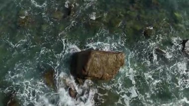 Dev okyanus dalgaları, büyük kaya taşlarıyla boş kumsallara çarpıp köpürüyor.. 