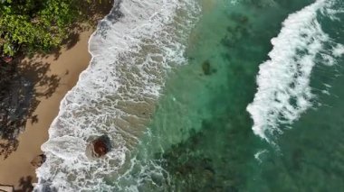 Dev okyanus dalgaları, büyük kaya taşlarıyla boş kumsallara çarpıp köpürüyor.. 