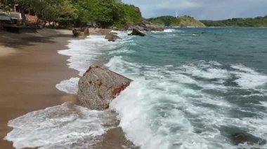 Dev okyanus dalgaları, büyük kaya taşlarıyla boş kumsallara çarpıp köpürüyor.. 