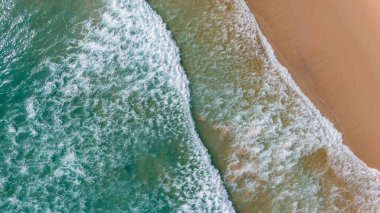 Kumlu sahile vuran dalgalarla dolu bir sahile..