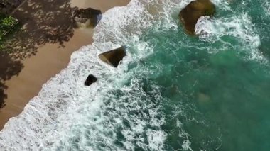 Dev okyanus dalgaları, büyük kaya taşlarıyla boş kumsallara çarpıp köpürüyor.. 