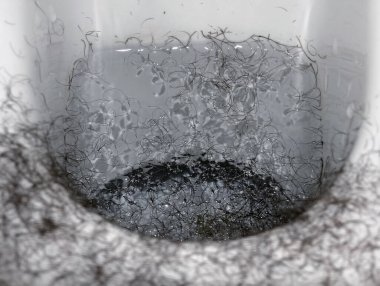 Tıraş makinesiyle kesilmiş saçlarla dolu bir klozet..