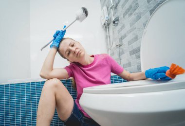 Genç ev hanımı banyodaki klozeti özenle temizler ve yıkar..