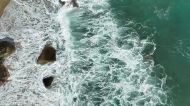 Dev okyanus dalgaları, büyük kaya taşlarıyla boş kumsallara çarpıp köpürüyor.. 