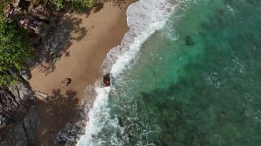 Dev okyanus dalgaları, büyük kaya taşlarıyla boş kumsallara çarpıp köpürüyor.. 