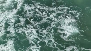 Dev okyanus dalgaları, büyük kaya taşlarıyla boş kumsallara çarpıp köpürüyor.. 