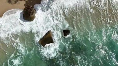 Dev okyanus dalgaları, büyük kaya taşlarıyla boş kumsallara çarpıp köpürüyor.. 