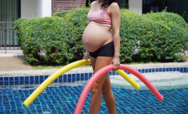 Bilardo oynamak üzere olan hamile genç kadın köpüklü makarnayla havuzda egzersiz yapacak..