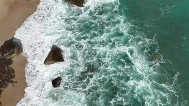 Dev okyanus dalgaları, büyük kaya taşlarıyla boş kumsallara çarpıp köpürüyor.. 