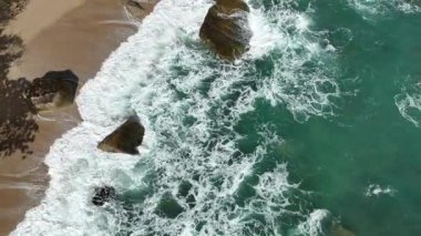 Dev okyanus dalgaları, büyük kaya taşlarıyla boş kumsallara çarpıp köpürüyor.. 