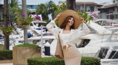 Bagajlı genç kadın yat limanının yanında yürüyor..