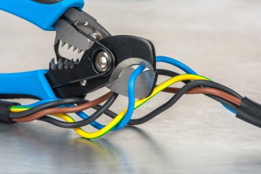 Metal atölye masasında kerpeten ve elektrik kablosu kesiliyor.