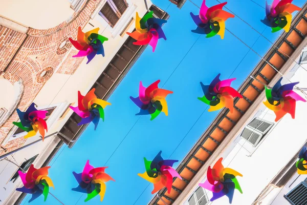 Colored rainbow fan hanging between buildings, street decoration
