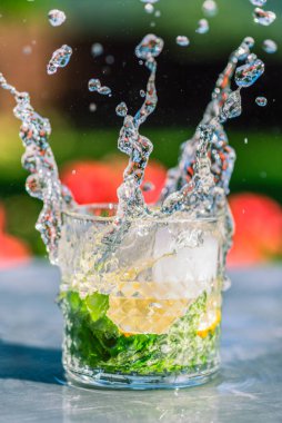 Camdan naneli su sıçrıyor, metal masanın üzerinde duruyor.