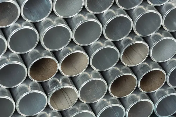 Stack of old aluminum pipes with light reflections
