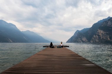 Garda Gölü 'nün rıhtımında meditasyon yapan iki kadın.