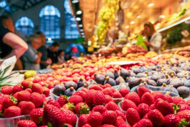 Çilek ve kivi meyveli bir tezgah, arka planda satıcılar ve alıcılar, Valencia 'da yerel bir gıda pazarının salonunda