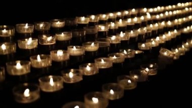 Siyah arkaplanda yanan çok sayıda küçük mum